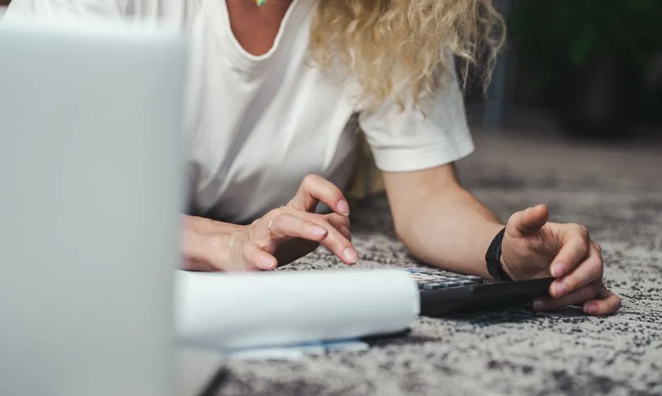A person reviewing paperwork with a calculator at home