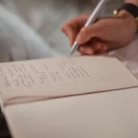 A hand writing notes in an open journal