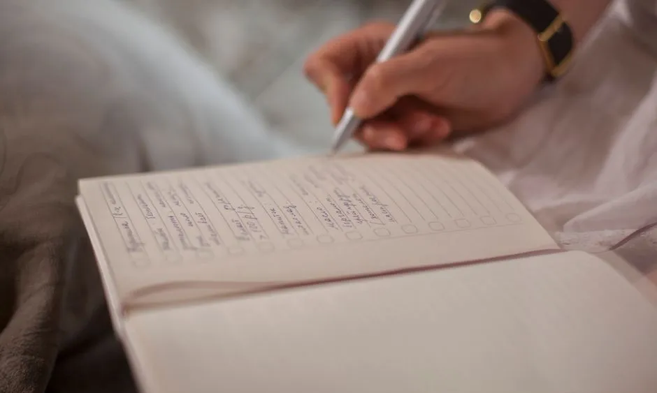 A hand writing notes in an open journal
