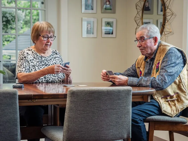 An older couple playing cards together at their dining table