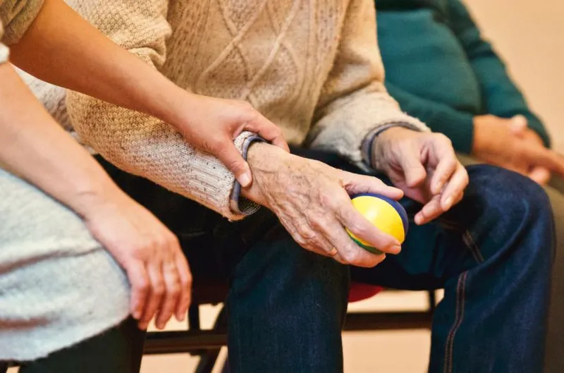 A caregiver gently holding an older adult's hand
